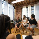 women sitting on chairs inside a room public speaking
